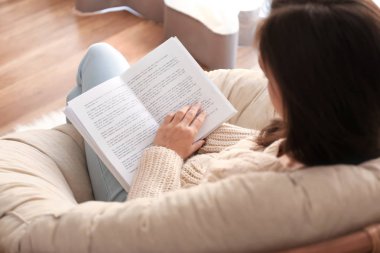 Genç kadın evde şezlong üzerinde kitap okuma