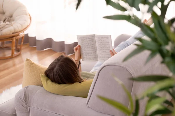 若い女性が家でソファで本を読んで — ストック写真