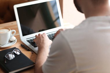 Kafede çalışan dizüstü bilgisayar ile genç serbest meslek