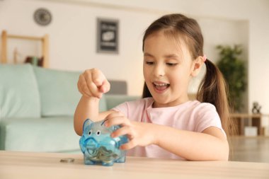 Küçük kız paralar kumbara kapalı koyarak. Para tasarruf kavramı