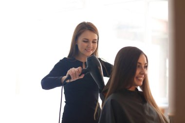 Profesyonel kuaför müşteriyle kuaförde çalışıyor.