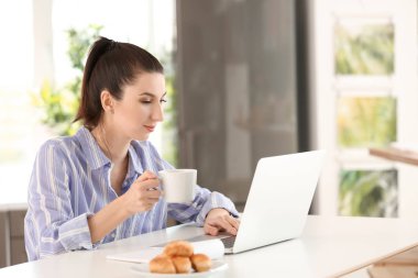 Genç kadın serbest meslek sahibi evde laptop ile çalışırken kahve içme
