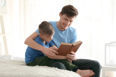 Baba ve oğlu birlikte evde kitap okuma