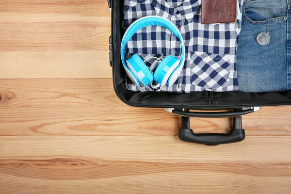 服や木製の背景に観光客のものを開いているスーツケース — ストック写真