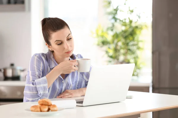 自宅のノート パソコンで作業しながらコーヒーを飲む若い女性フリーランサー — ストック写真