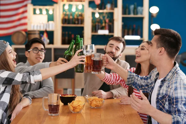 Group of cheerful friends drinking beer in bar