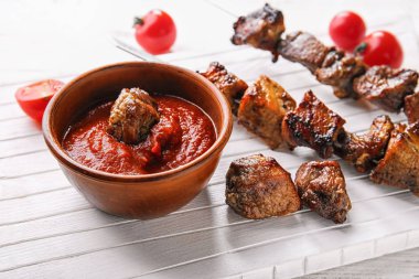 Ahşap tahta üzerinde kapta domates soslu sulu şiş kebap