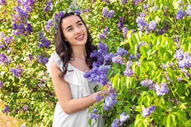 Çiçek çelenk çiçek açması çalı yakınındaki güneşli bahar gününde giyen güzel genç kadın