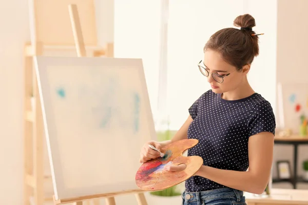 Female artist with palette and paint in workshop