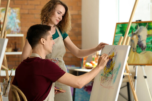 Female teacher helping her student during classes in school of painters