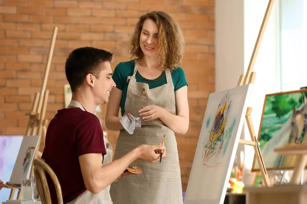 Female teacher helping her student during classes in school of painters