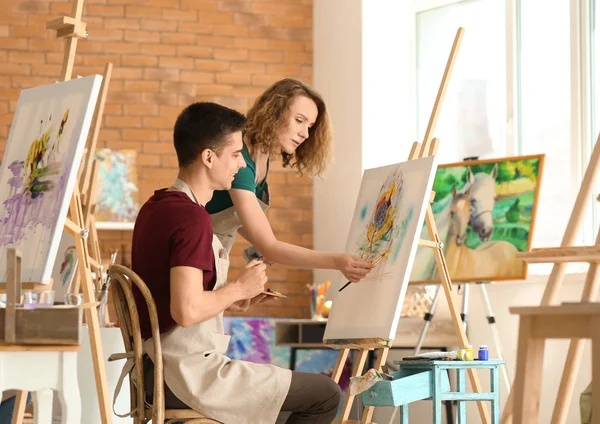 Female teacher helping her student during classes in school of painters