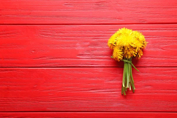 Yellow dandelions on color wooden background