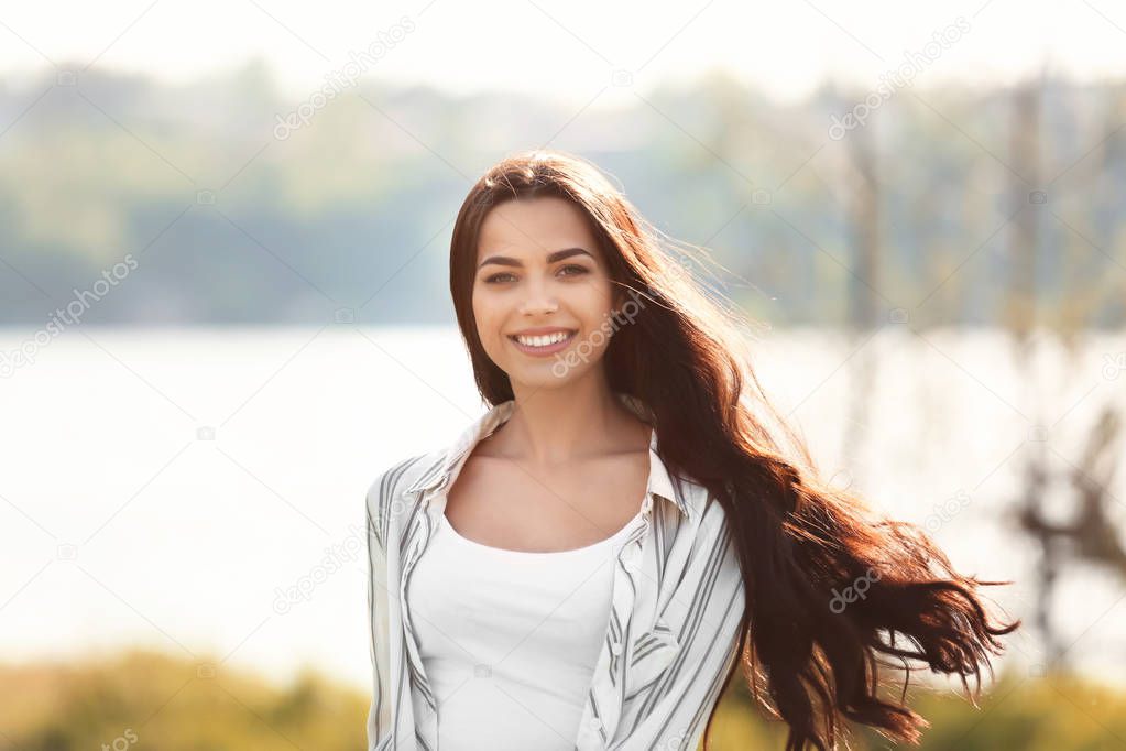 Beautiful young woman near river on spring day