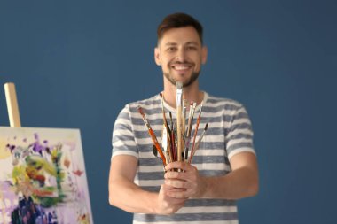 Boya araçları renk arka plan üzerinde tutan erkek sanatçı