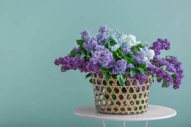 Güzel çiçek açması leylak rengi arka plan karşı masada ile hasır kutu