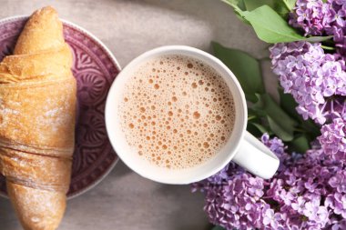 Fincan kahve ve masada güzel çiçek açması Lila ile lezzetli kruvasan