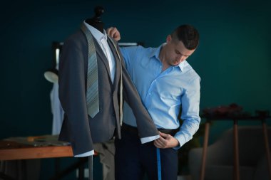 Atelier manken üzerinde ceket ölçümleri alarak genç terzi