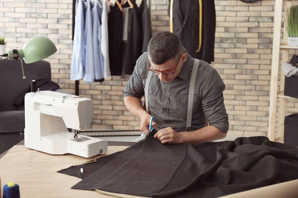 Молодой портной режущей ткани в ателье
