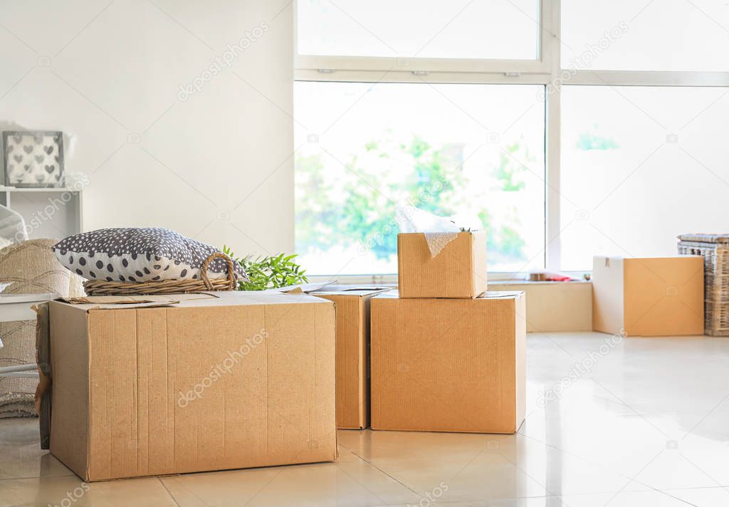 Carton boxes and interior items on floor in room. Moving house concept