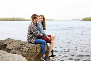 Bahar gününde nehir kenarında oturan mutlu genç çift