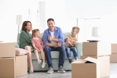 Kanepe kapalı kutuları yanında oturan mutlu bir aile. Yeni evime taşınmaya
