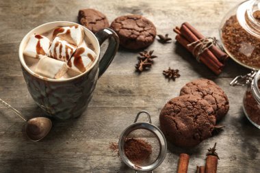 Şekerleme ve ahşap arka plan üzerinde çerezler ile lezzetli sıcak kakao fincan