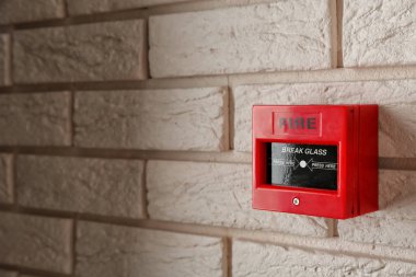 Modern fire call point on brick wall indoors clipart
