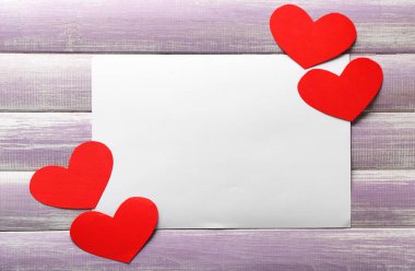 Kırmızı kağıt kalpleri ve ahşap arka plan üzerinde boş kartı