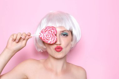 Peruk ve lolipop renk arka plan üzerinde olan kadın