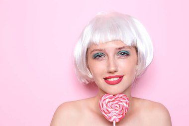 Peruk ve lolipop renk arka plan üzerinde olan kadın