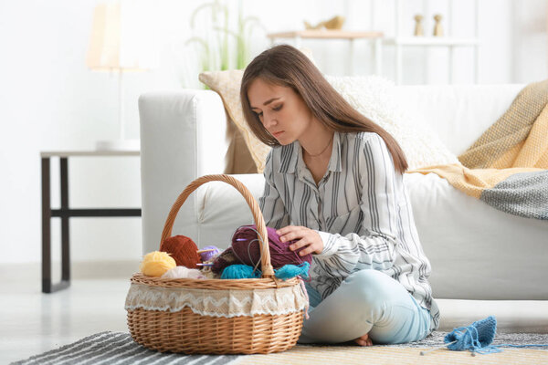 Young woman choosing color of knitting threads at home