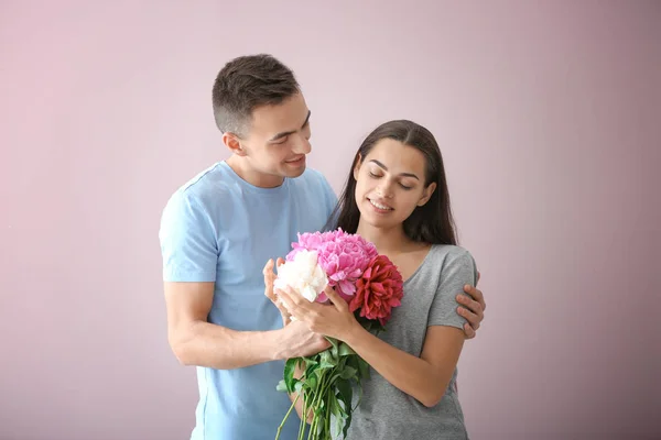 Young Man Giving Beautiful Flowers His Beloved Girlfriend Color Background — Stock Photo, Image
