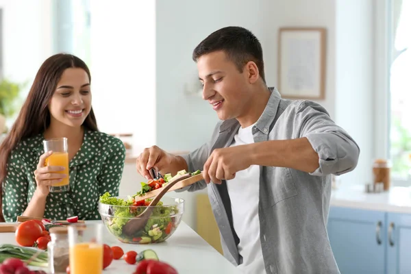 Young man cooking with his girlfriend in kitchen