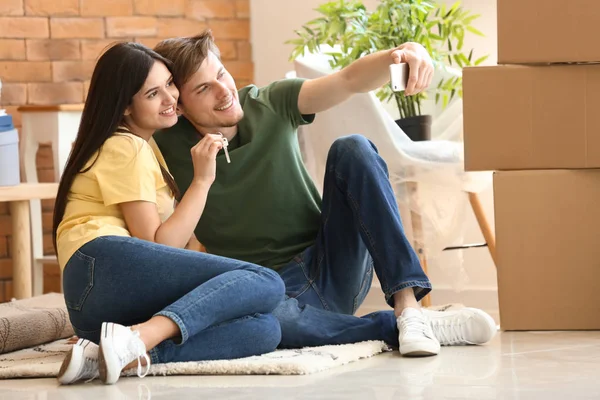 Joven Pareja Feliz Tomando Selfie Con Llave Nueva Casa Interior — Foto de Stock