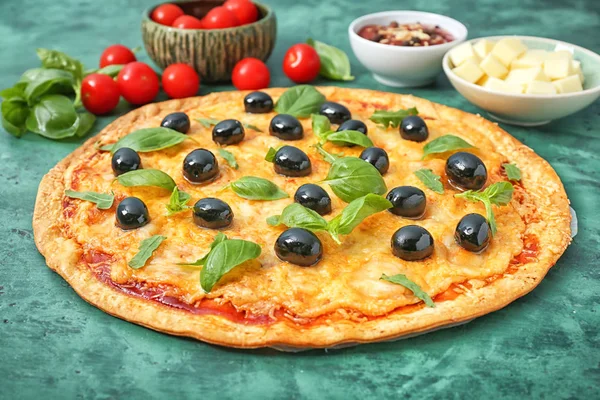 Tasty pizza with olives and ingredients on color background