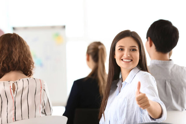 Молодая женщина показывает большой палец вверх жест во время деловой встречи в офисе
