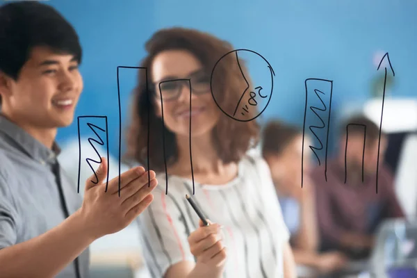 People discussing diagram drawn on transparent board during business meeting