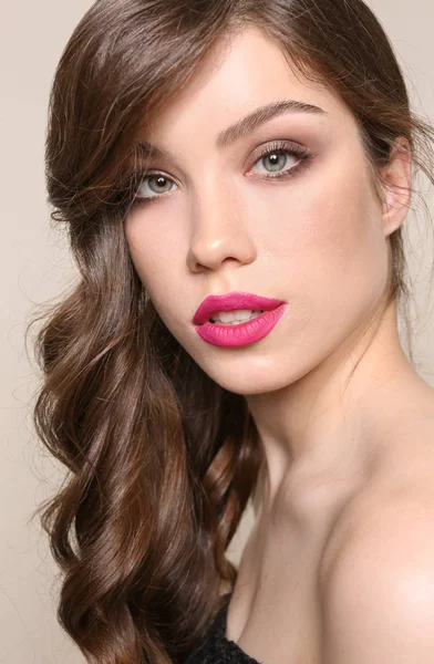 Portrait of young woman with professional makeup on grey background