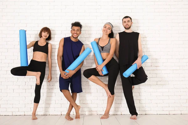 Grup Yoga Paspaslar Yakınındaki Beyaz Tuğla Duvar Ile Sportif Insan — Stok fotoğraf