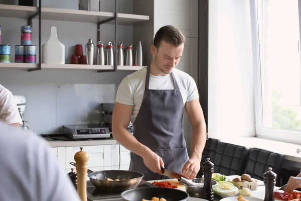 Joven guapo hombre cocina en la cocina del restaurante durante las clases de cocina —  Fotos de Stock