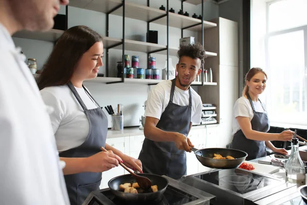 Jovens durante aulas de culinária na cozinha do restaurante — Fotografia de Stock