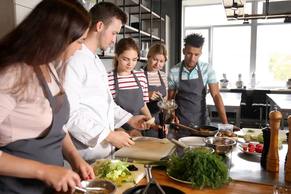 Chef-kok en groep jongeren tijdens kooklessen — Stockfoto