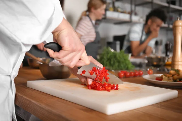 Mannelijke chef-kok snijden groenten tijdens kooklessen, close-up — Stockfoto