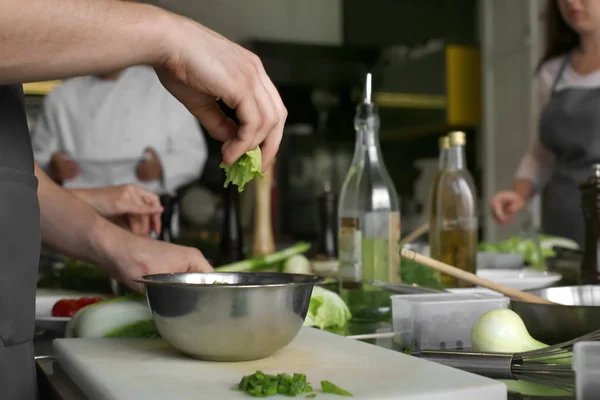Jovem prepara salada na cozinha do restaurante durante as aulas de culinária — Fotografia de Stock