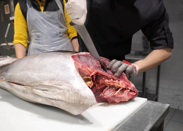 Uomo che taglia tonno fresco in tavola nel mercato del pesce — Foto Stock