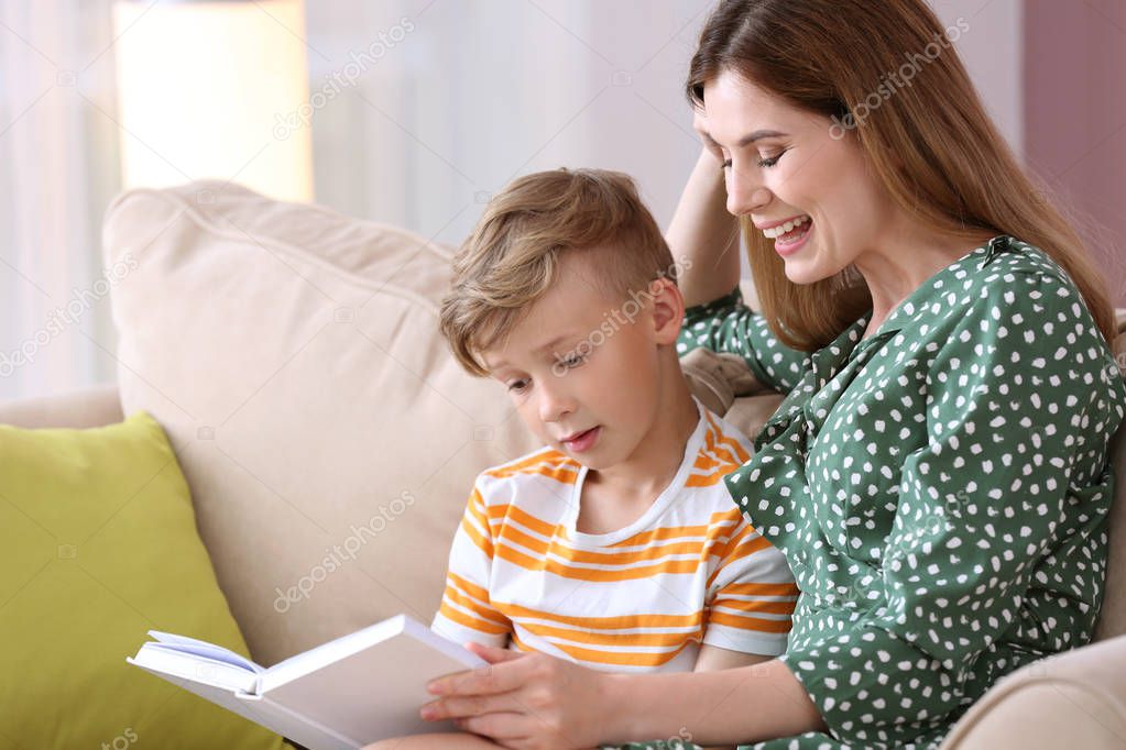 Mother and her son reading book together at home