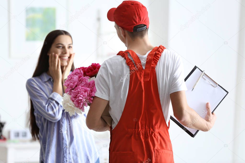 Young woman receiving beautiful flowers from delivery man