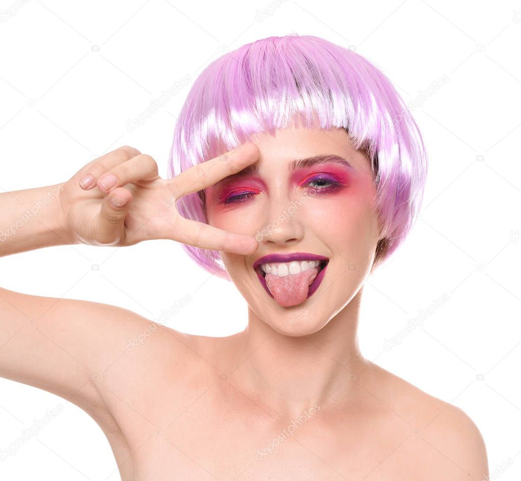Young woman with unusual hair and professional makeup showing victory gesture on white background