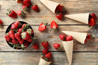 Ahşap masa üzerinde tatlı olgun çilek ile kase ve gözleme koniler